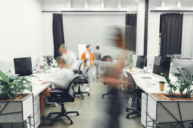 An open-plan office with people moving in a blur