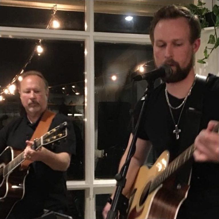 Ed and Alex playing acoustic guitars and singing together